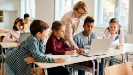 Lehrerin mit SchülerInnen (ca. 12 Jahre alt) vor einem Computer im Klassenzimmer